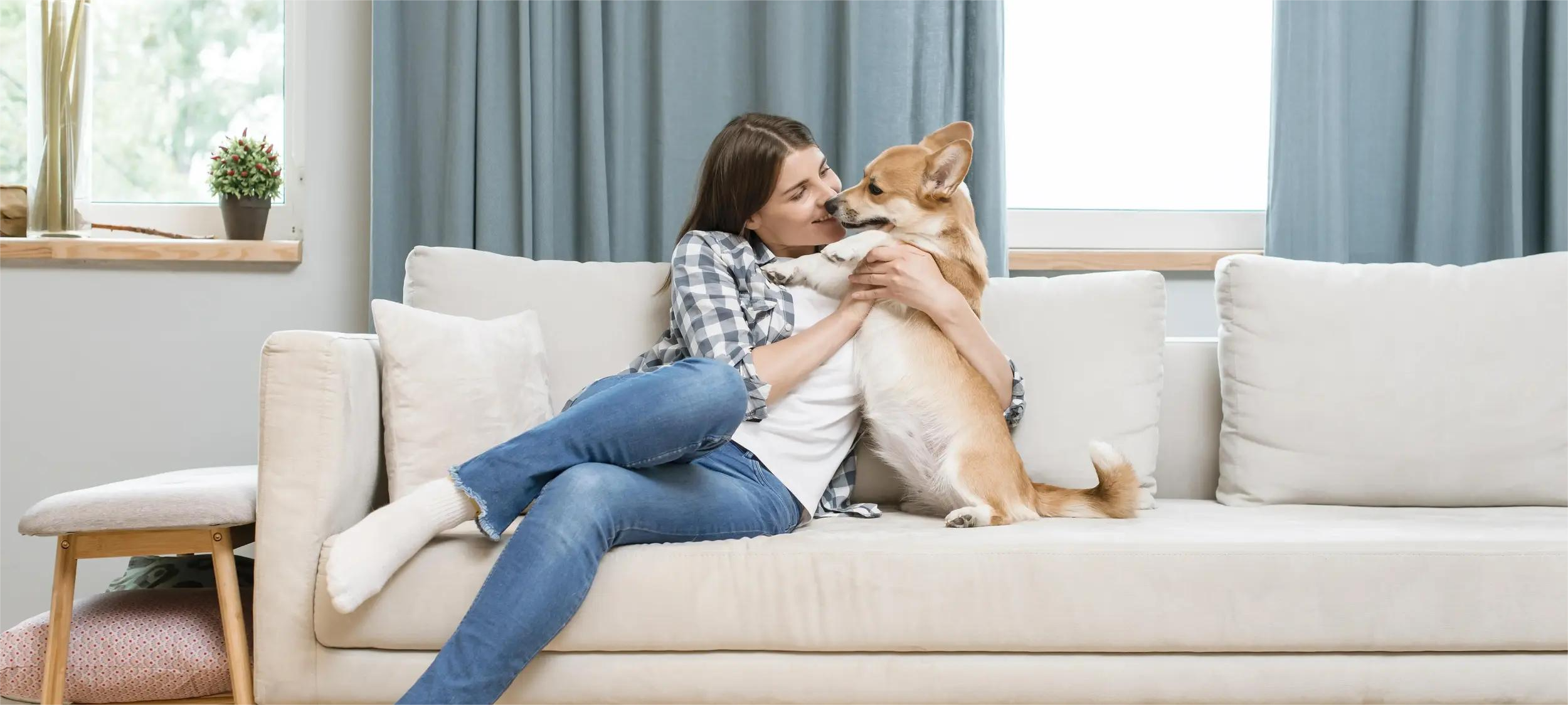 Woman sitting on a couch with a dog, surrounded by home decor.